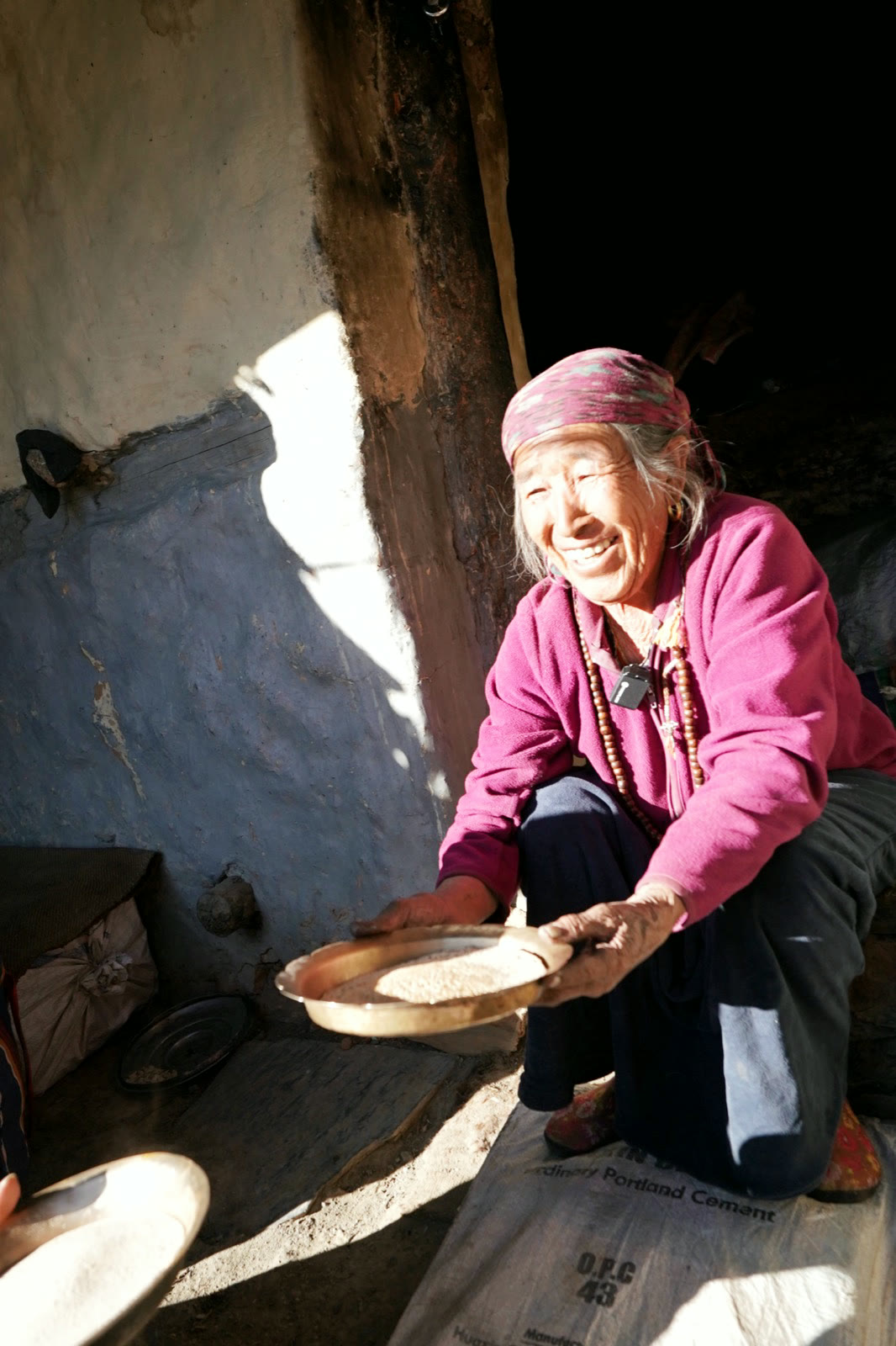 村中婦人在屋內篩穀,光自高處落下